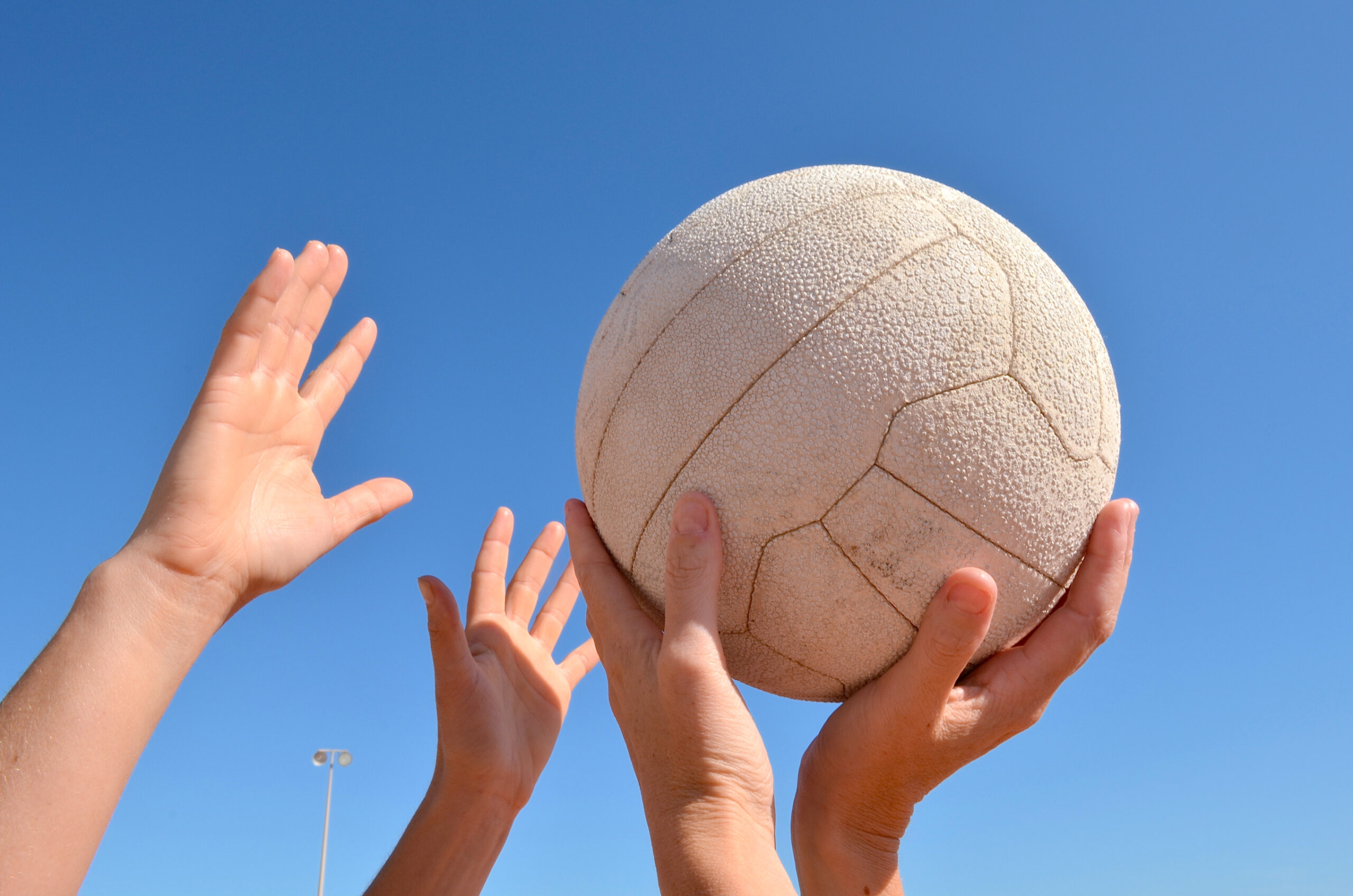 Hands reaching for a netball