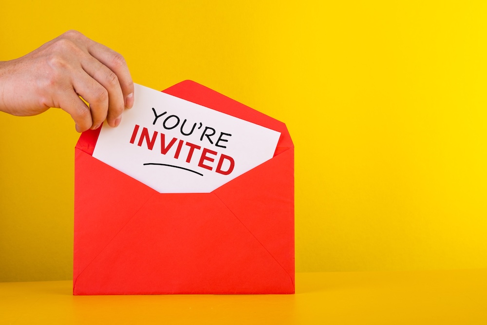 You're Invited Concepts - Hand holding a a card with red envelope.